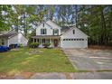 Inviting two-story home featuring white siding, green shutters, mature trees, and attached two car garage at 4500 Hollirose Pl, Raleigh, NC 27616