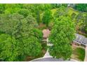 Aerial view showcases the brick home nestled among mature trees and lush greenery in a serene setting at 101 Easton Ct, Garner, NC 27529