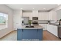 Bright kitchen features stainless steel appliances, white cabinets, and a blue island with granite countertop at 1073 Branch Line Ln, Apex, NC 27502