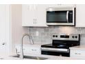 Modern kitchen features stainless steel appliances, gray tile backsplash, and stylish chrome water faucet at 147 Little Crk Dr, Lillington, NC 27546