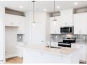 Bright kitchen boasts modern appliances, white cabinets, a stylish island and designer pendant lights at 147 Little Crk Dr, Lillington, NC 27546
