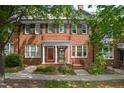 Beautiful red brick townhomes with green shutters and charming flower garden at 1508 W Markham Ave, Durham, NC 27705