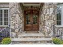 Elegant stone entryway with a custom double-door entrance and iron railings at 1605 Hunting Ridge Rd, Raleigh, NC 27615