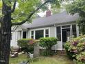Exterior view of a charming home with grey siding, mature trees and beautiful azalea bushes at 1812 House Ave, Durham, NC 27707