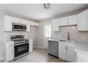 Well-lit kitchen with stainless appliances, white cabinets, tiled backsplash, and a door leading to the outside at 1903 Meadowbrook St, Sanford, NC 27330