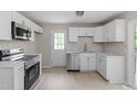 Modern kitchen with stainless steel appliances, white cabinets, light countertops, and stylish tile backsplash at 1903 Meadowbrook St, Sanford, NC 27330