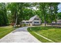 Two-story home with lush green yard and mature trees, showcasing a paved driveway and cozy front porch at 1915 Redding Ln, Durham, NC 27712