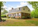 Brick home with a gambrel roof and manicured landscaping creates inviting curb appeal at 2021 Sunnybrook Dr, Burlington, NC 27215