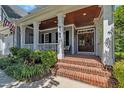 Close-up of a charming front porch with brick steps, white columns, and a beautiful wood-stained front door at 2723 Cameron Pond Dr, Cary, NC 27519