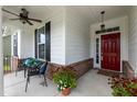 Cozy front porch with seating, decorative plants, brick accents, and a vibrant red front door at 273 Scarlet Tanager Cir, Holly Springs, NC 27540