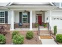Inviting front porch with brick accents, seating, and a view of the landscaped yard at 273 Scarlet Tanager Cir, Holly Springs, NC 27540