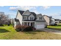 Two-story light-green home with manicured yard and attached two car garage on a sunny day at 323 Windgate Dr, Clayton, NC 27527
