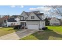 View of the light-green home showing attached garage and manicured lawn on a sunny day at 323 Windgate Dr, Clayton, NC 27527