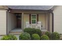 Covered front porch featuring rocking chairs, manicured shrubs, and a front door at 4005 Colleen Way, Kittrell, NC 27544