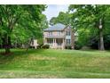 Inviting two-story brick home with covered front porch, surrounded by mature trees on a well-manicured lawn at 5112 Wolcott Ct, Fuquay Varina, NC 27526