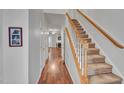 Inviting hallway featuring wood floors, staircase with carpet and white trim, and white doors at 5547 Sea Daisy Dr, Raleigh, NC 27606
