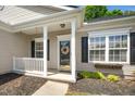Close-up of a cozy front porch with a decorative wreath, black shutters, and neatly landscaped flower box at 8300 Neuse Hunter Dr, Raleigh, NC 27616