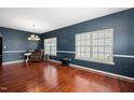 Bright living room showcasing hardwood floors, large windows, and dark blue walls complemented by elegant white trim at 8300 Neuse Hunter Dr, Raleigh, NC 27616