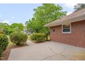 Brick home featuring a concrete patio area surrounded by manicured shrubbery at 1105 Hargrove St, Henderson, NC 27536