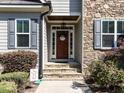 Inviting front entrance with a stone facade, a stylish wooden door, and well manicured shrubs at 1108 Kalworth Rd, Wake Forest, NC 27587
