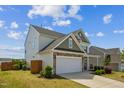 A side view of a two-story home highlighting the attached two-car garage and landscaping at 115 Bourne Dr, Franklinton, NC 27525