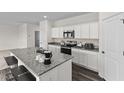Modern kitchen features granite countertops, an island with breakfast bar, and white cabinets at 141 Gladstone Loop, Clayton, NC 27520