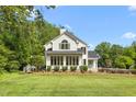 Charming white home with lots of windows surrounded by lush greenery and well-manicured lawn at 1925 W Lake Dr, Burlington, NC 27215
