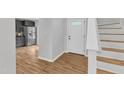 Bright foyer featuring hardwood floors, staircase, and view into modern kitchen with stainless steel appliances at 221 Mint Hill Dr, Cary, NC 27519