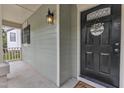 Inviting front porch featuring a stylish black door with a 'welcome' wreath and charming exterior lighting at 221 Mint Hill Dr, Cary, NC 27519