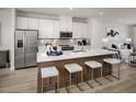 Modern kitchen features a quartz-topped island with seating, stainless steel appliances, and white cabinetry at 2881 Foster Woods Dr, Apex, NC 27502
