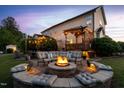 Inviting backyard with a stone fire pit, comfortable seating, and a pergola-covered deck illuminated with string lights at 48 Falling Oak Ct, Clayton, NC 27520