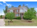 Attractive brick home featuring manicured lawn, mature trees, and a classic architectural design at 5004 Clowser Minnow Ct, Wake Forest, NC 27587