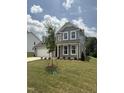 Attractive gray home showcasing a landscaped front yard and inviting covered entryway at 567 Winding Creek Dr, Lillington, NC 27546
