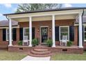 Inviting front porch with classic columns, brick accents, rocking chairs, and stylish black shutters at 603 Warren Rd, Erwin, NC 28339
