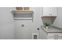 Bright laundry room with upper cabinets, utility sink, and granite countertops for efficient cleaning and storage at 1733 Birdhaven Ln, Wendell, NC 27591