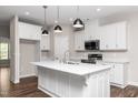 Modern kitchen with white cabinets, stainless steel appliances, a large island and pendant lights at 186 N Ashe Ave, Dunn, NC 28334