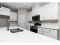 Bright kitchen with stainless steel sink, black appliances, white cabinets and marble countertops at 186 N Ashe Ave, Dunn, NC 28334