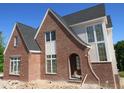 New brick home with a steep gabled roof, an arched doorway, and multiple windows at 2590 Silas Peak Ln, Apex, NC 27523