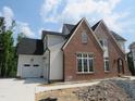 Two-story new home with brick and white siding, three car garage, and unfinished landscaping at 2590 Silas Peak Ln, Apex, NC 27523