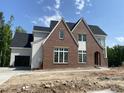 View of new construction with red brick, black roof, white trim, and attached garage at 2590 Silas Peak Ln, Apex, NC 27523