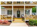 Inviting front porch featuring wood detail, stylish seating, and blooming potted plants at 27 Ashley Woods Ct, Clayton, NC 27527