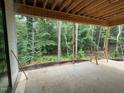 Covered porch with exposed wood rafters overlooking a private backyard full of mature trees at 3324 Founding Place, Raleigh, NC 27612