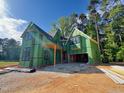 New home in construction phase with green weather resistant barrier, black windows, and a bright blue sky at 3324 Founding Place, Raleigh, NC 27612