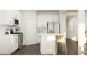 Open concept kitchen with white cabinets, stainless steel appliances, a central island, and hardwood floors at 4017 Shadbush St, Raleigh, NC 27616