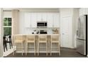 Bright kitchen featuring white cabinets, stainless steel appliances, a center island with seating, and wood flooring at 4017 Shadbush St, Raleigh, NC 27616