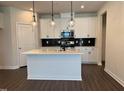 Modern kitchen featuring white cabinets, a kitchen island, stainless steel appliances, and stylish pendant lighting at 604 Hyperion Aly, Wake Forest, NC 27587