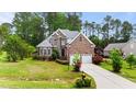 Charming two-story brick home with a two-car garage, lush green lawn, and well-maintained landscaping at 7405 Pine Summit Dr, Fuquay Varina, NC 27526