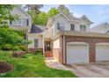 Charming exterior view of home with brick details, lush landscaping, and a two car garage at 7705 Astoria Pl, Raleigh, NC 27612