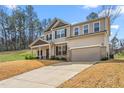 Inviting two-story home displaying a covered front porch, an attached two-car garage, and a spacious driveway at 1009 Haynoke Dr, Graham, NC 27253