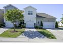 Rear view of townhomes featuring individual garages, well-maintained landscaping, and freshly cut lawns on a sunny day at 124 Shale Creek Dr, Durham, NC 27703